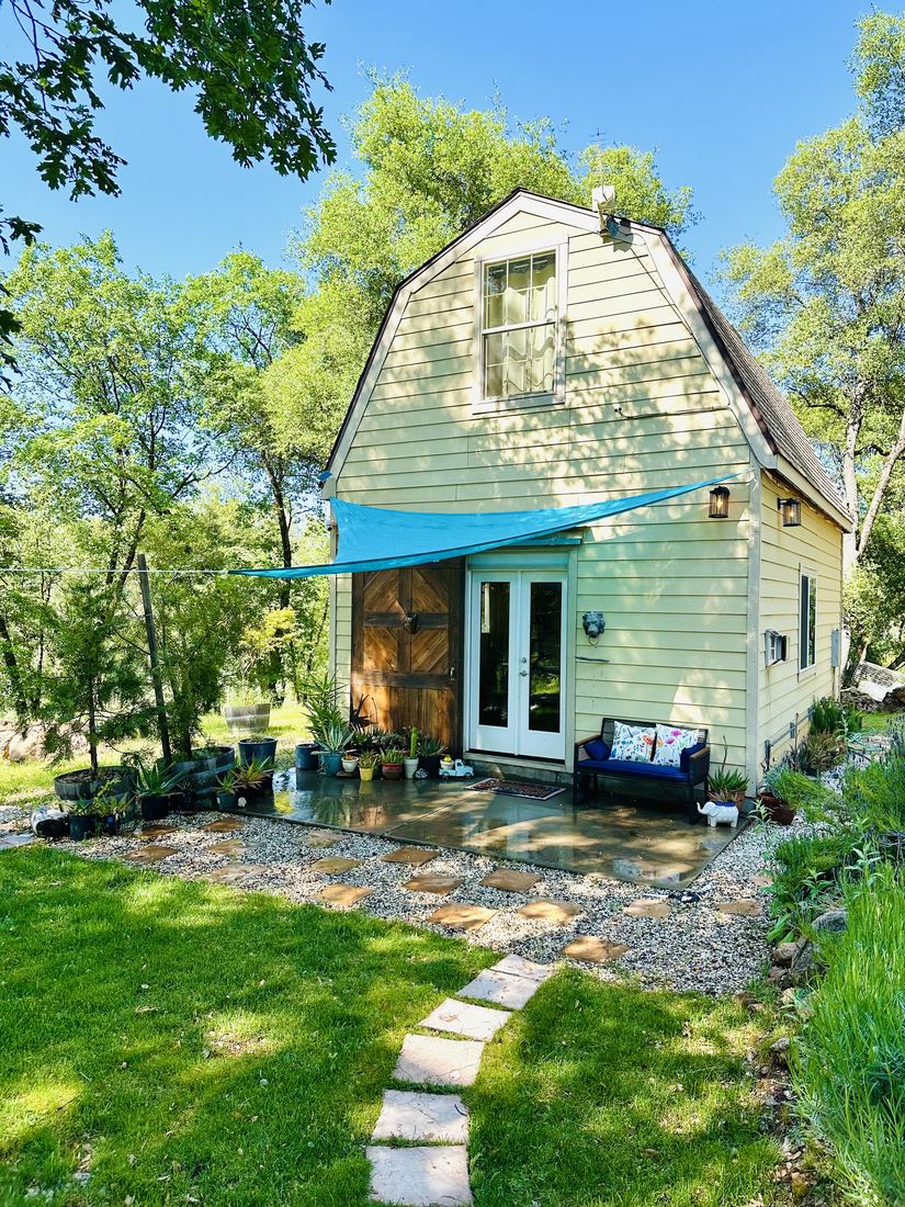The cottage with its blue awning, stone path and green lawn